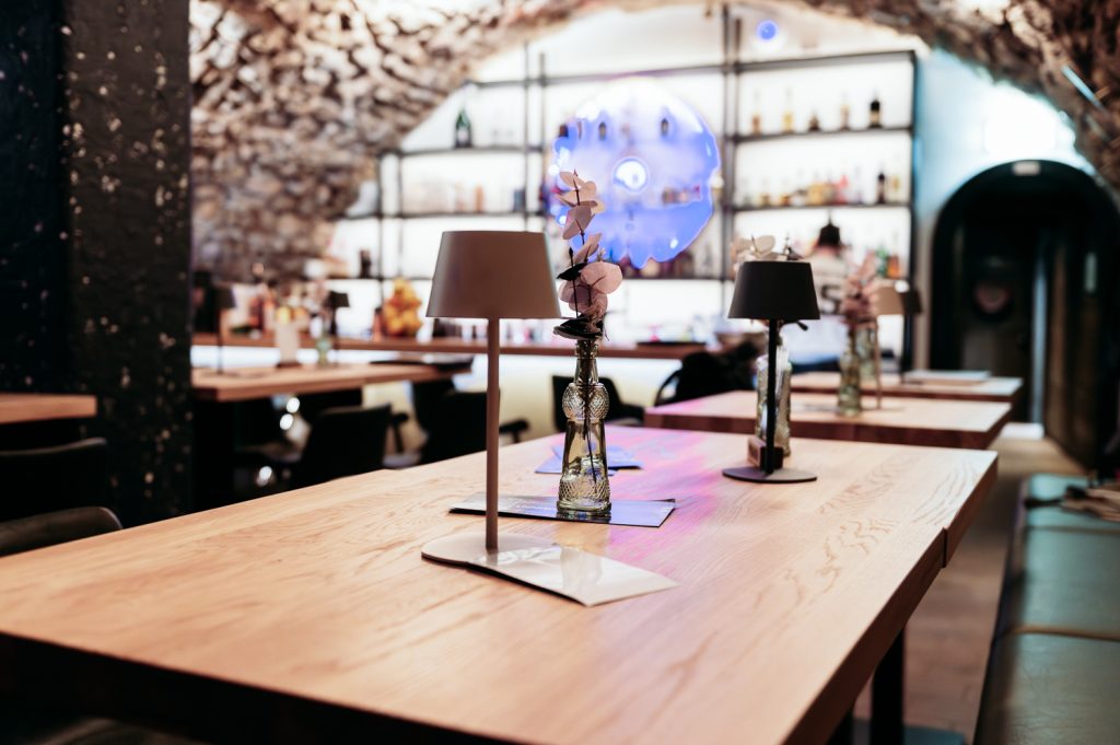 Holztische mit Tischlampen vor der Bar im Gewölbekeller des Löwenkeller Roth